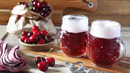 Light fruit craft beer and cherry on wooden chopping board, rustic style
