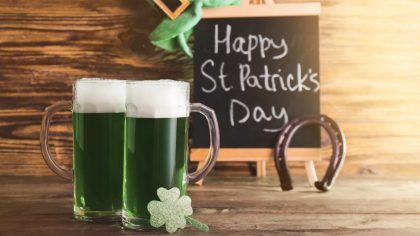 Mugs of green beer for St. Patrick's Day on wooden table