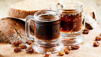 Traditional Russian drink kvass in a mug, with rye bread on a wooden background in rustic style, selective focus