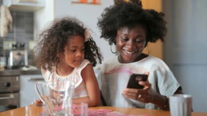 Mother and little daughter smiling while looking at phone