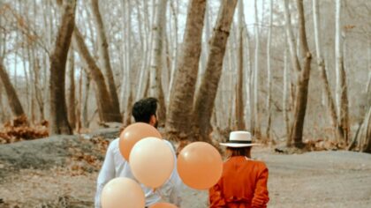 A couple walking while holding balloons