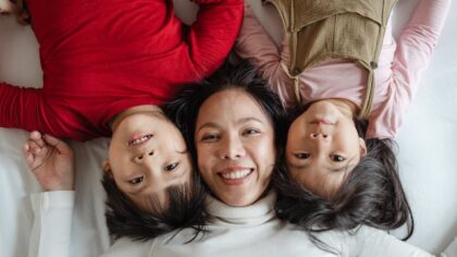 Mother is lying on the bed with her kids