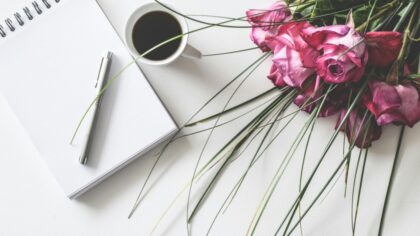 Notebook with pen, coffee and pink roses