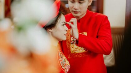 Asian groom touching face of stylish bride